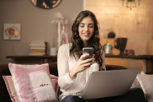 First home buyer reviewing property finances on her phone and laptop at home